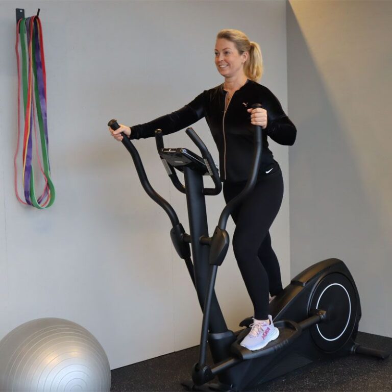 Kvinna som tränar på en crosstrainer på gymmet