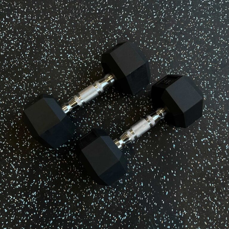 Ett par hexhantlar på ett svart gymgolv med ett ljust mönster