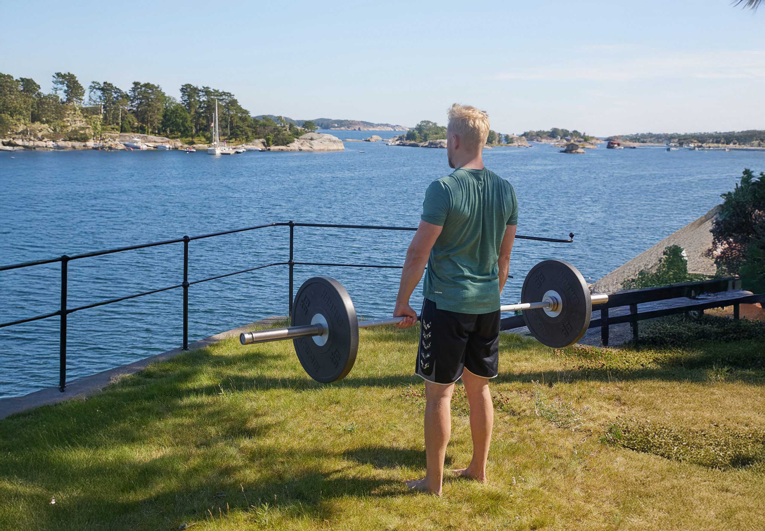 En man som tränar med en skivstång vid vattnet
